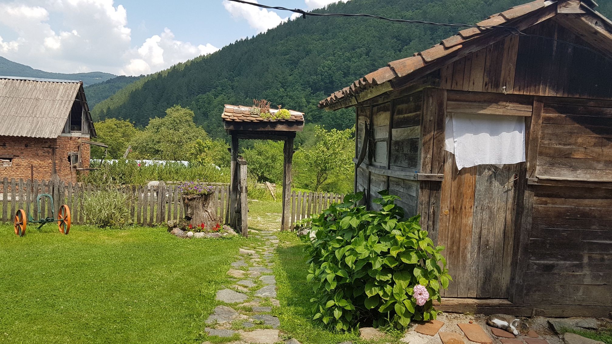 Dvorište sa kamenim pločama i starinskom drvenom kapijom